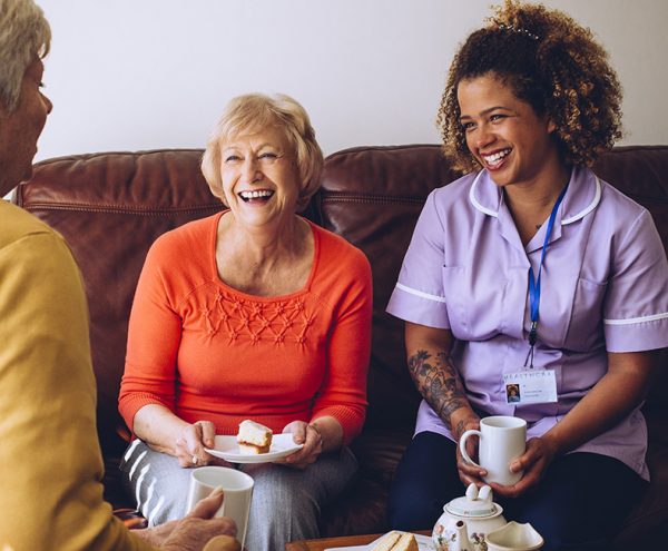 Carer laughing with a collection of residents