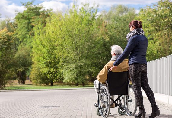 Carer pushing an elderly man in a wheelchair