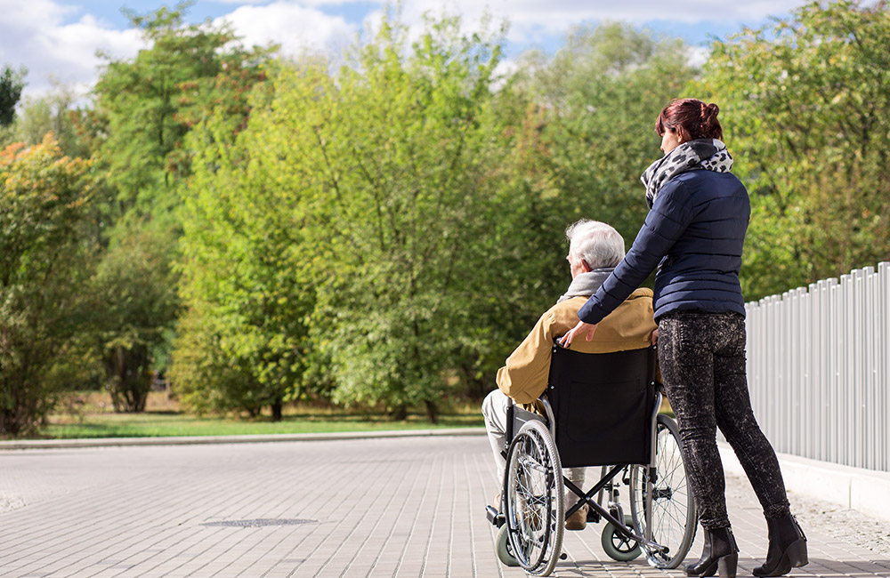 Carer pushing an elderly man in a wheelchair