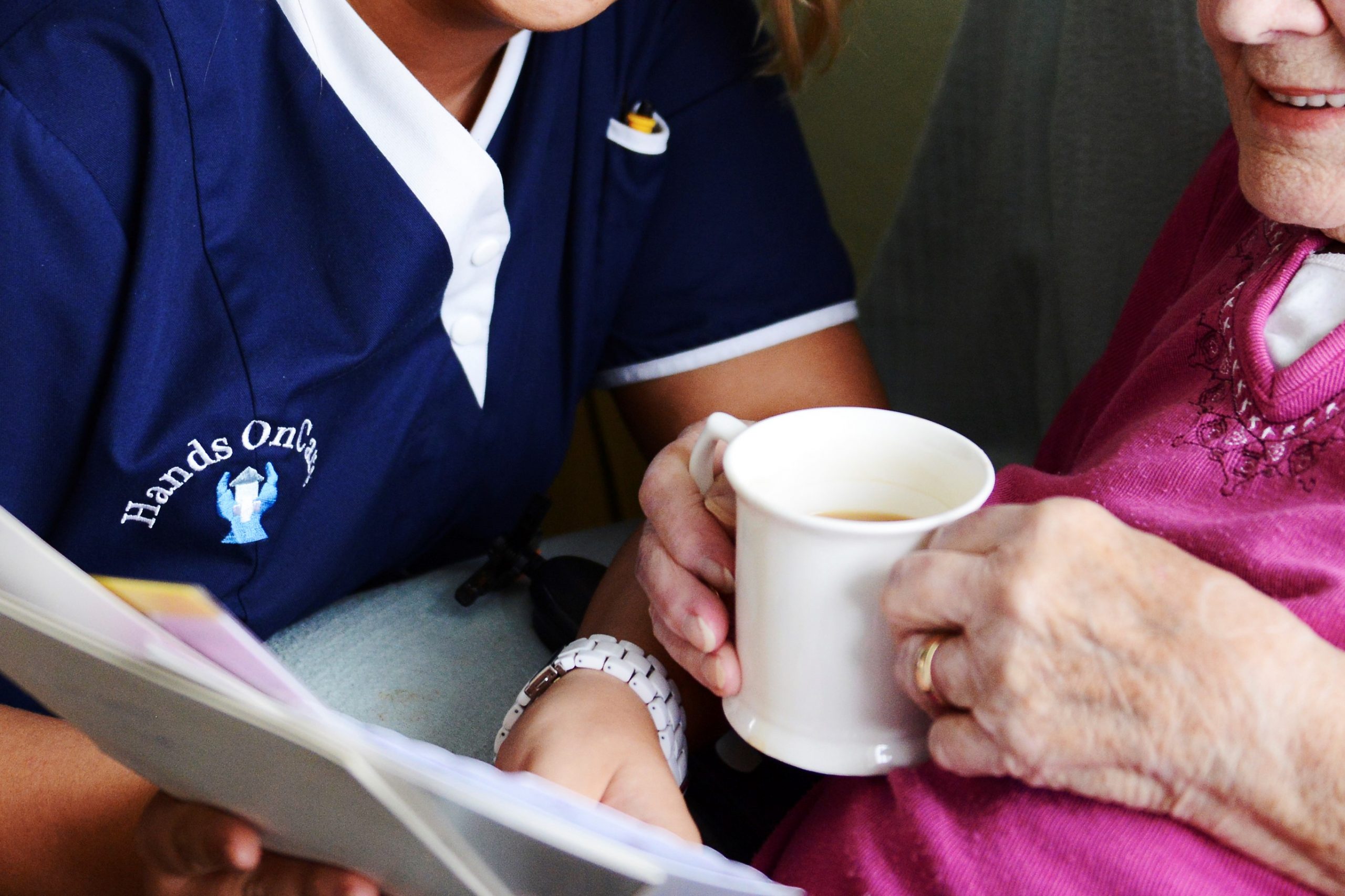 Hands on Care caregiver talking to a resident holding a cup of tea