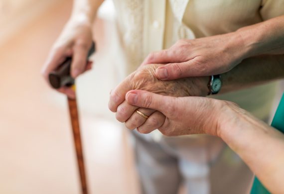 Caregiver looking after elderly person and helping them walk