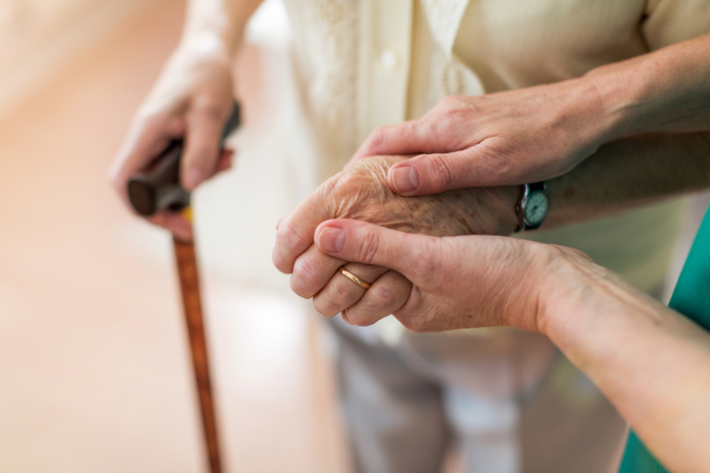 Caregiver looking after elderly person and helping them walk