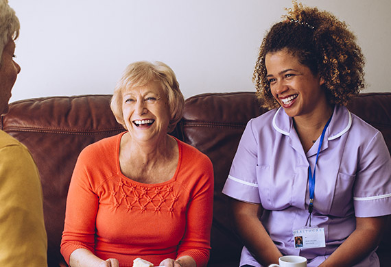 A resident laughing with a caregiver on a sofa