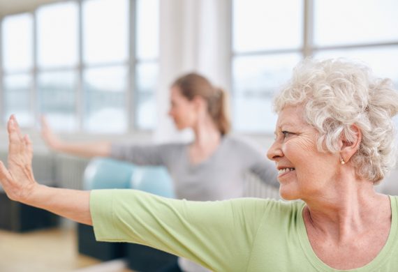 Silver haired woman smiling as she is performing exercise