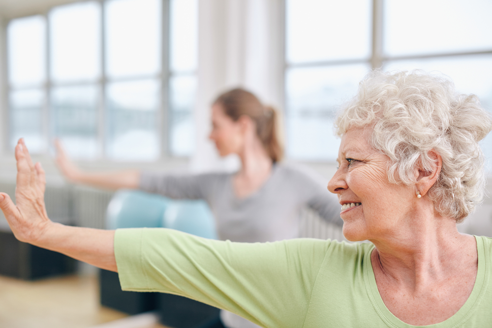 Silver haired woman smiling as she is performing exercise