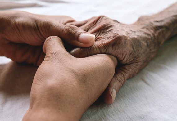 An elderly persons hand being gripped