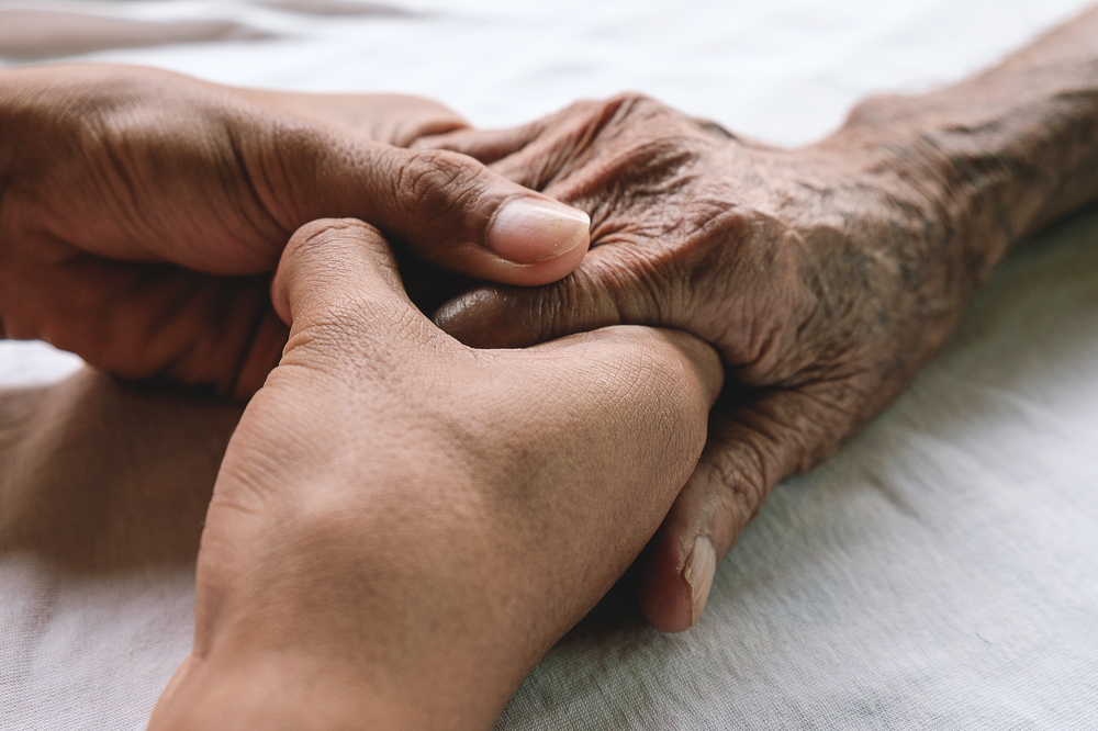 An elderly persons hand being gripped