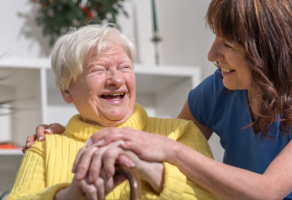 An elderly person smiling and laughing with a caregiver.