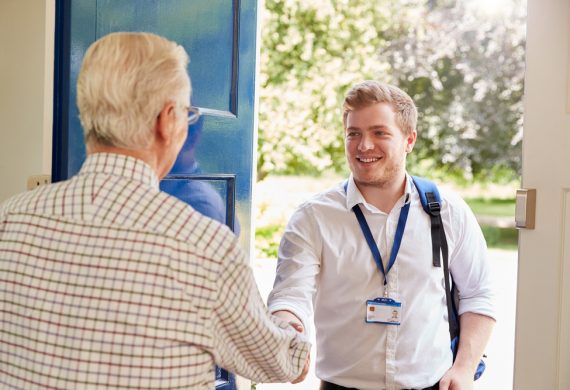 Caregiver greeting an elderly person at the door