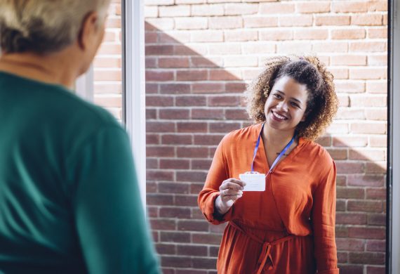 Female caregiver smiling at someone before they enter the home