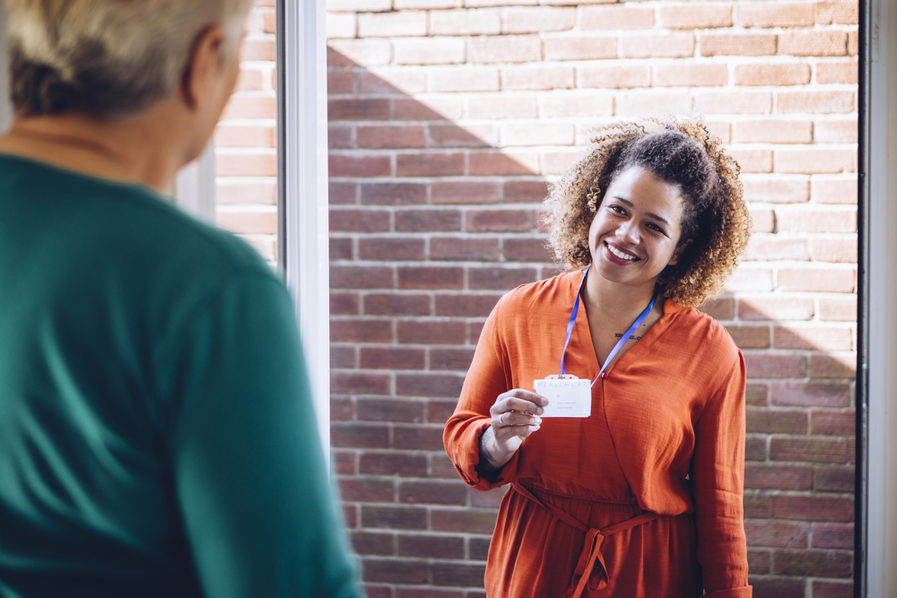 Female caregiver smiling at someone before they enter the home