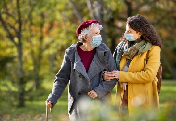 Caregiver helping a woman through on walk through a park