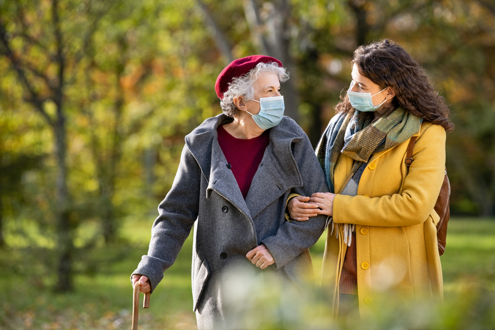 Caregiver helping a woman through on walk through a park